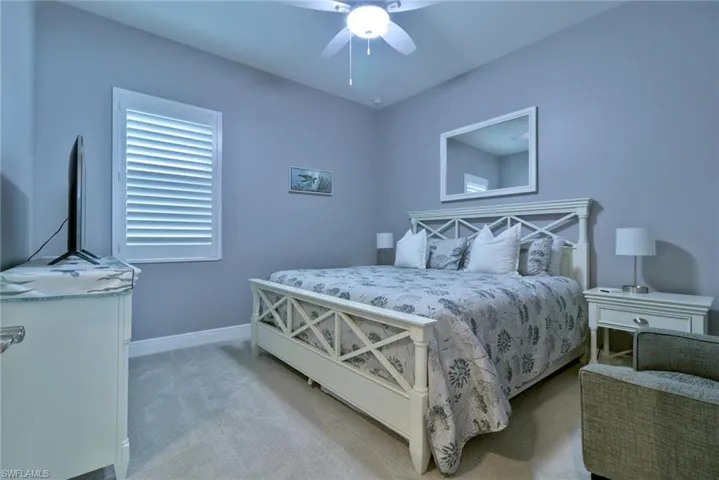 Guest bedroom with plantation shutters and a ceiling fan light