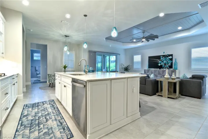 Kitchen featuring the large center island with a Quartz countertop and shaker cabinets, Stainless Steel dishwasher and modern pendant lighting.