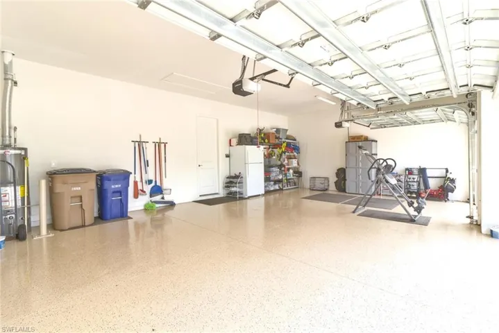 Garage with a garage door opener, white fridge, and water heater