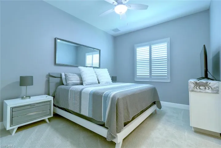 Guest bedroom with plantation shutters and a ceiling fan light