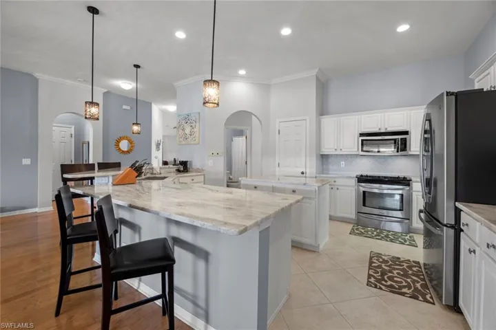 Private hall on left to Master Suite and hall, behind island is pantry and archway to private hall to 3rd full bath and a 4th bedroom/office/study