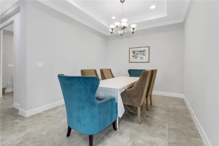 Dining area featuring a tray ceiling, an inviting chandelier, and ornamental molding