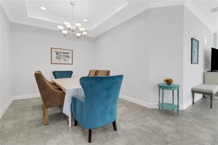 Dining space featuring a tray ceiling, crown molding, and a notable chandelier