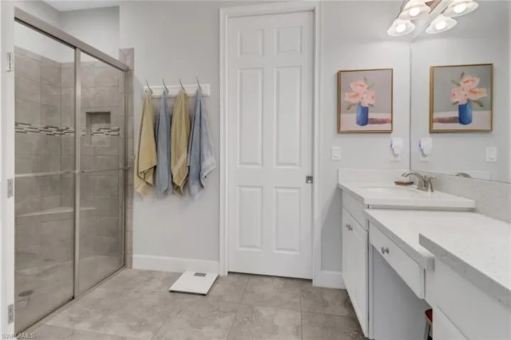 Bathroom featuring tile patterned floors, vanity, and a shower with shower door