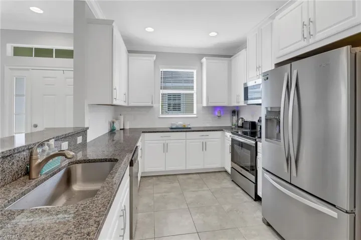 Kitchen with white cabinetry, sink, and appliances with stainless steel finishes