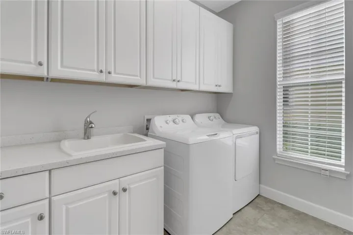 Washroom featuring washing machine and clothes dryer, sink, and cabinets