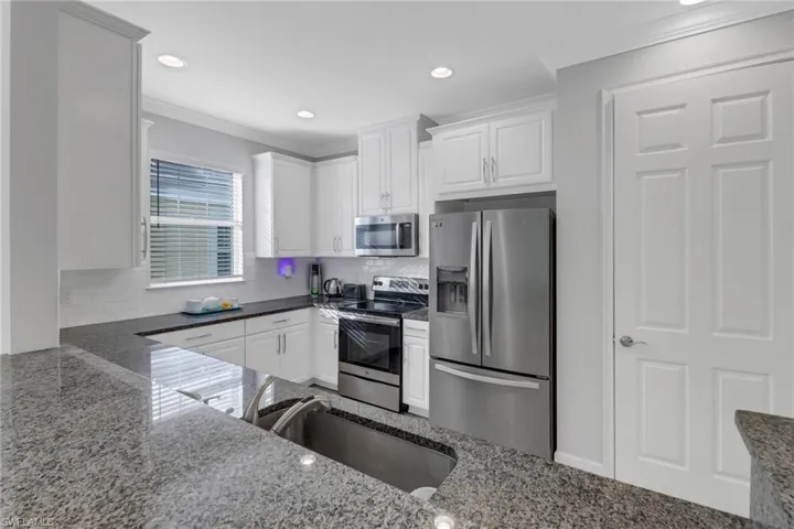 Kitchen featuring white cabinets, sink, dark stone countertops, and stainless steel appliances