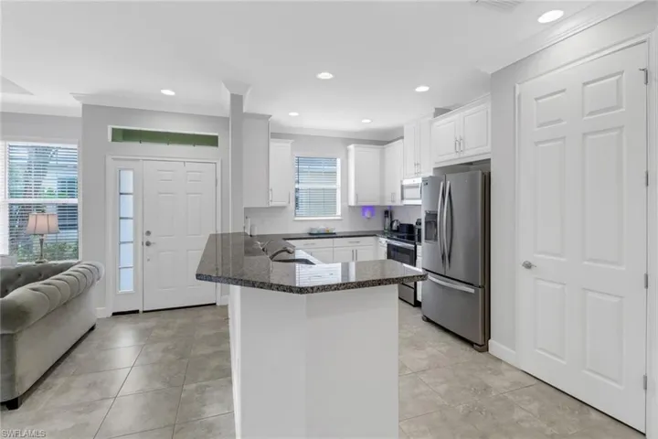 Kitchen featuring white cabinetry, tasteful backsplash, kitchen peninsula, crown molding, and appliances with stainless steel finishes