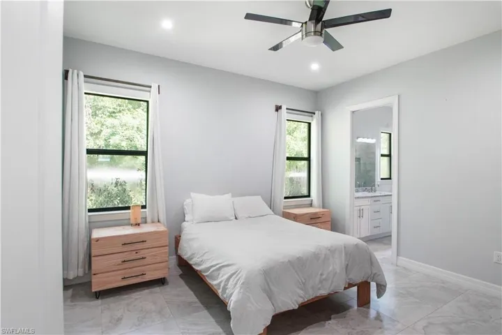 Bedroom featuring ensuite bathroom, ceiling fan, and light tile floors