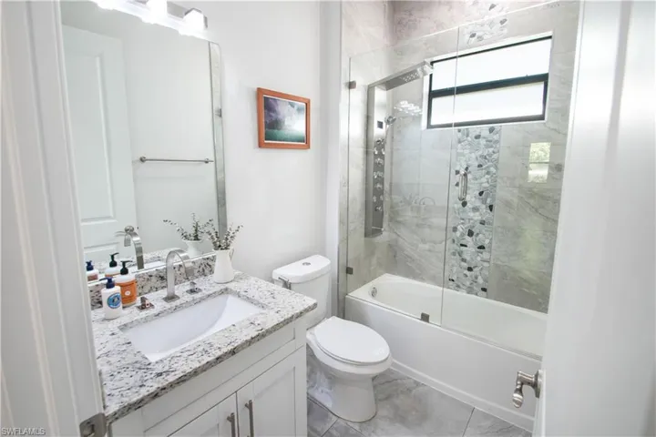 Full bathroom featuring tile flooring, vanity, toilet, and tiled shower / bath combo