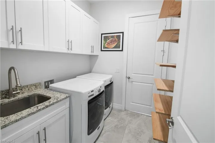 Clothes washing area featuring independent washer and dryer, washer hookup, light tile floors, sink, and cabinets