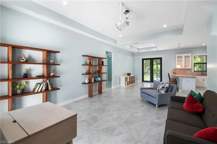 Living room with french doors, light tile floors, and a raised ceiling