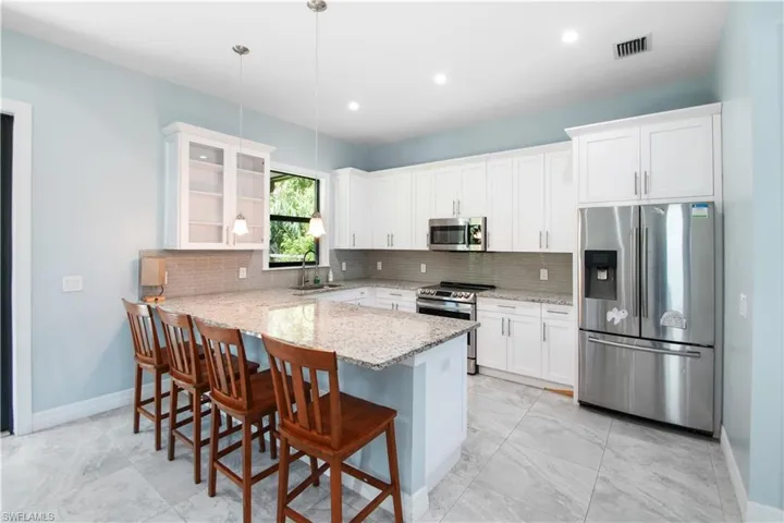 Kitchen featuring white cabinetry, appliances with stainless steel finishes, backsplash, sink, and light tile floors