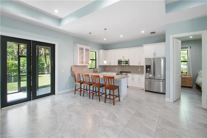 Kitchen with appliances with stainless steel finishes, white cabinetry, tasteful backsplash, and kitchen peninsula
