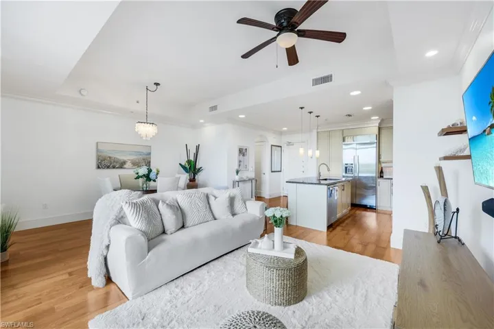 Living area featuring ornamental molding, light wood-style floors, a ceiling fan, a chandelier, and recessed lighting