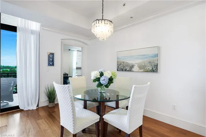 Dining room featuring crown molding, wood finished floors, a chandelier, and a tray ceiling
