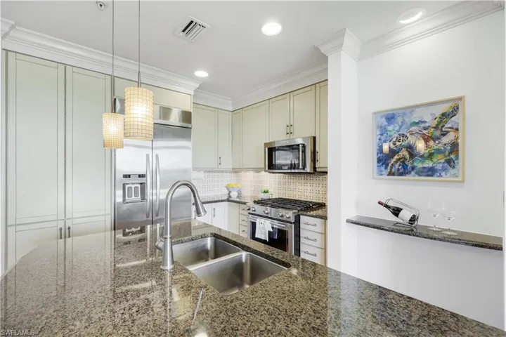 Kitchen with stainless steel finishes appliances, dark stone countertops, decorative backsplash, pendant lighting, and crown molding