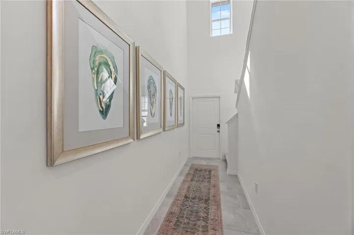 Hallway with a towering ceiling and baseboards