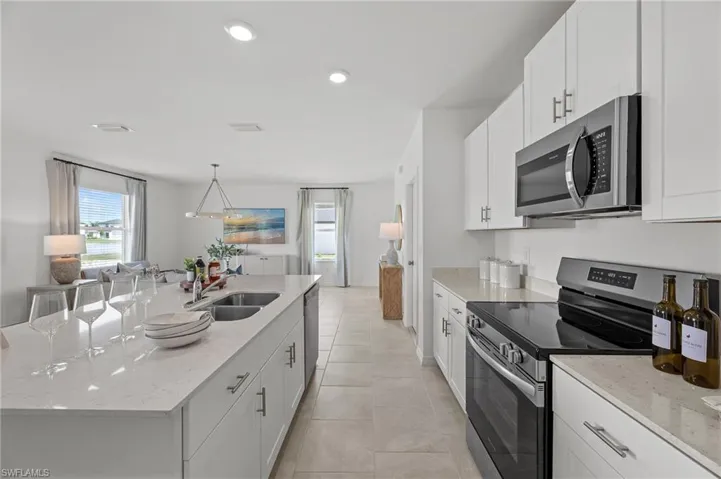 Kitchen with appliances with stainless steel finishes, plenty of natural light, a kitchen island with sink, white cabinetry, and recessed lighting