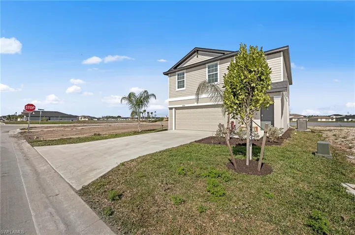 View of front of property featuring a garage, concrete driveway, and a front yard