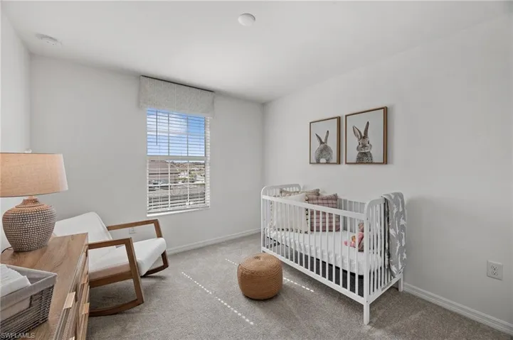 Carpeted bedroom featuring baseboards and a nursery area