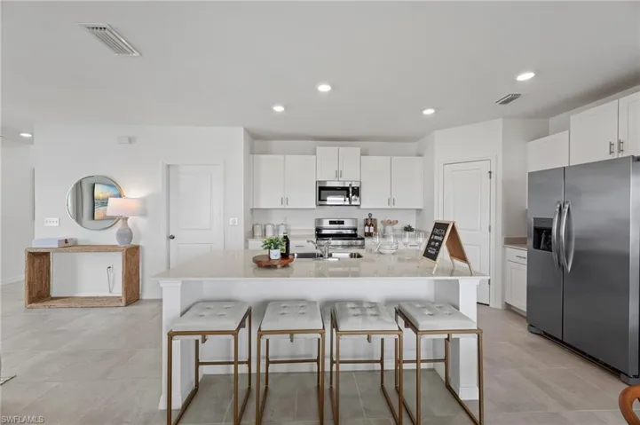 Kitchen featuring appliances with stainless steel finishes, a breakfast bar area, white cabinetry, and recessed lighting