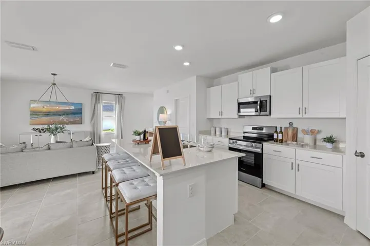 Kitchen with appliances with stainless steel finishes, white cabinets, a center island, and recessed lighting