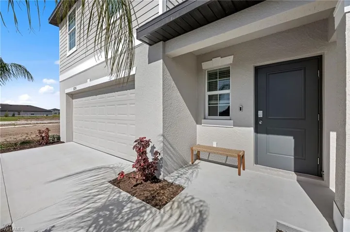 Doorway to property with an attached garage, stucco siding, and concrete driveway