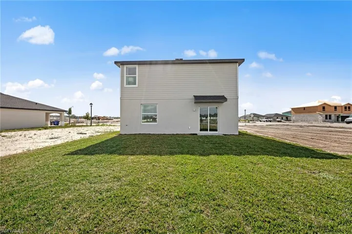 Back of property featuring a yard and stucco siding