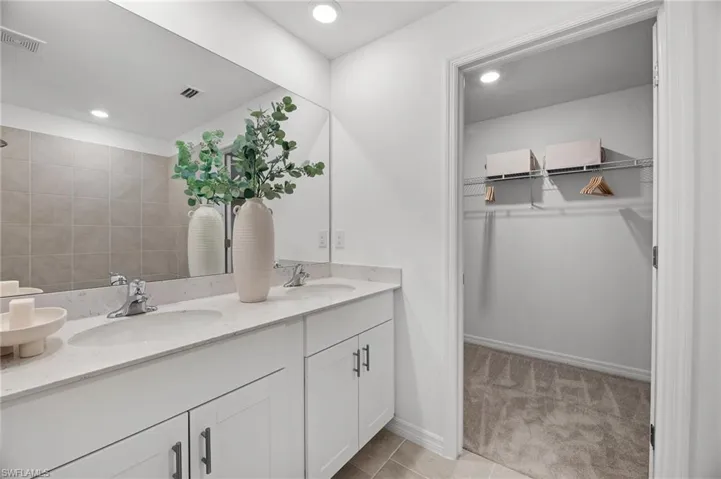 Full bath featuring double vanity, a walk in closet, and recessed lighting