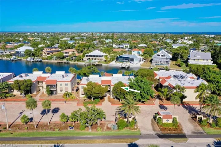 Waterfront community featuring multiple buildings, lush landscaping, and a clear water canal