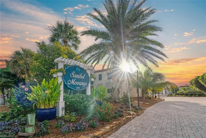 Sanibel Moorings entryway featuring lush landscaping, mature palm trees, and a paver driveway