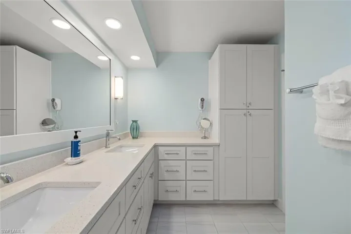 Extended vanity with dual undermount sinks, light-toned countertop, and white shaker-style cabinetry