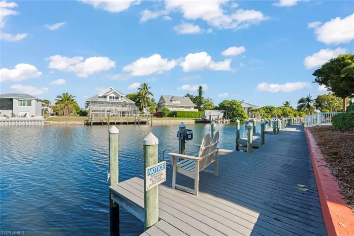 Waterfront property featuring an extensive dock with multiple boat slips, a fixed wooden dock, and a paved walkway