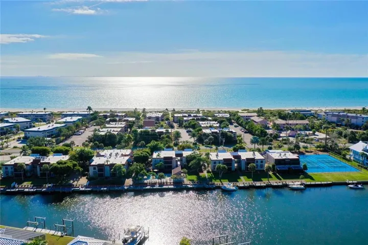 Coastal community featuring waterfront properties, a private dock with boats, a tennis court, and beach access