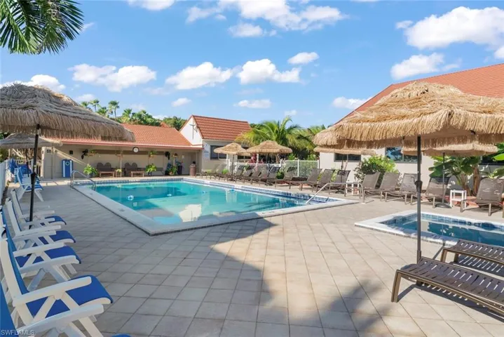 Resort-style pool area featuring a rectangular pool, integrated spa, and extensive tiled patio