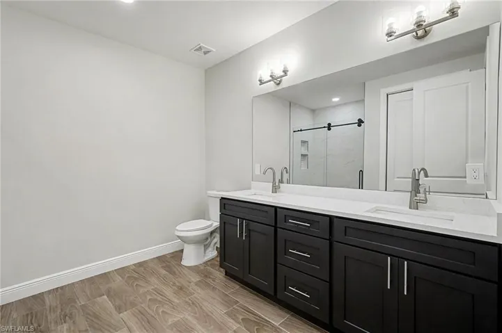 Full bath with double vanity, wood tiled floors, a marble finish shower, and recessed lighting