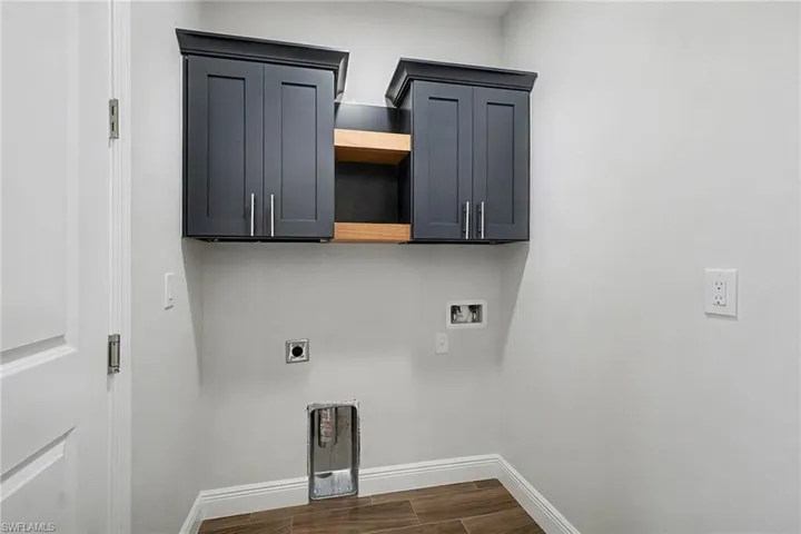 Washroom with cabinet space, hookup for an electric dryer, wood tiled floors, and hookup for a washing machine