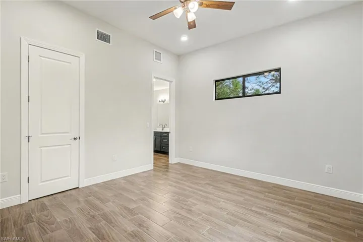 Unfurnished bedroom with wood finish floors, ceiling fan, and connected bathroom