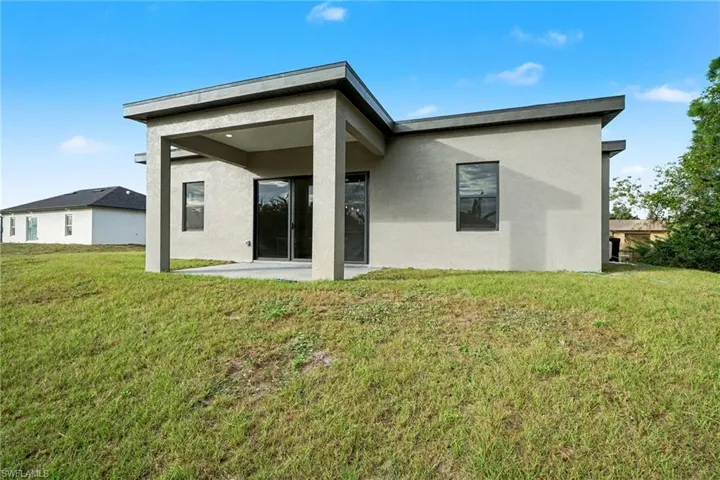 Rear view of house with a patio area, stucco siding, and a yard