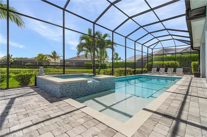 View of pool featuring a pool with connected hot tub, a patio area, and glass enclosure