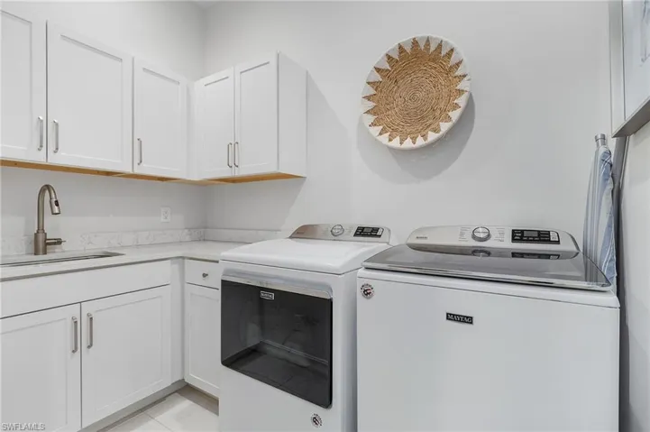 Laundry room featuring cabinet space, washing machine and clothes dryer, and light tile patterned floors