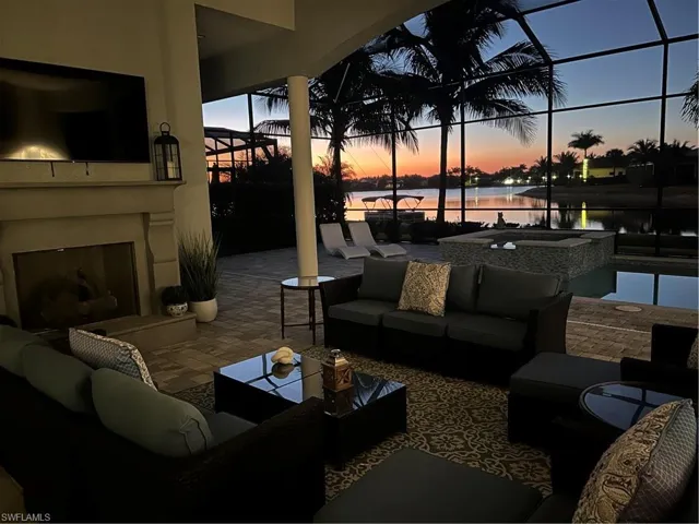 View of patio / terrace with an outdoor living space with a fireplace, glass enclosure, a water view, and a pool with connected hot tub
