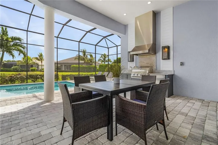 View of patio / terrace featuring exterior kitchen, an outdoor pool, glass enclosure, and outdoor dining area
