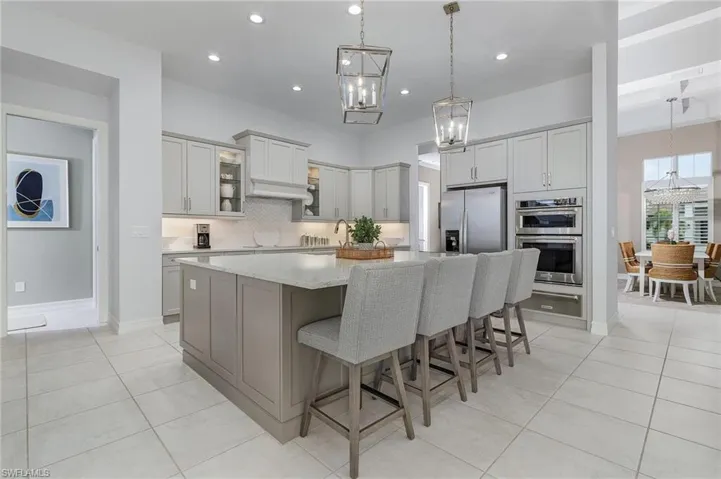 Kitchen with a large island, decorative backsplash, light tile patterned floors, a breakfast bar area, and recessed lighting