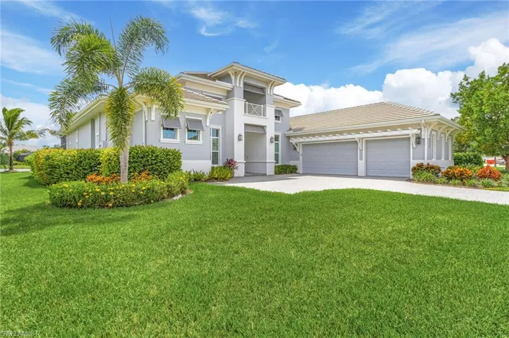 View of front of house with a tile roof, driveway, an attached garage, stucco siding, and a front lawn