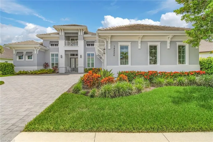 View of front of home with a tiled roof, decorative driveway, stucco siding, and a front yard