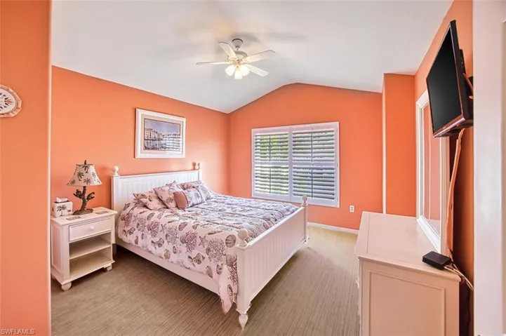 Carpeted bedroom with vaulted ceiling and a ceiling fan