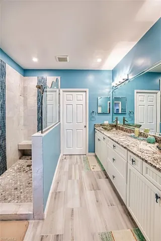 Bathroom featuring a walk in shower, vanity, and recessed lighting