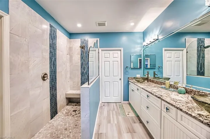 Bathroom with walk in shower, double vanity, and recessed lighting